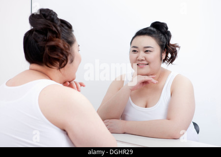 Una ragazza grassa guardando nello specchio Foto Stock