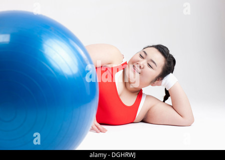 Una ragazza di grasso in una palestra outfit sdraiato sul pavimento Foto Stock