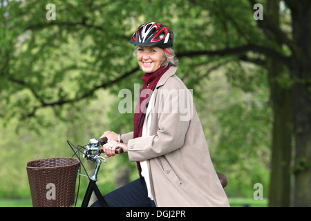 Senior donna bicicletta equitazione nel parco, ritratto Foto Stock