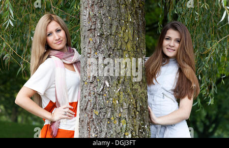Due giovani donne accanto a un tronco di albero Foto Stock