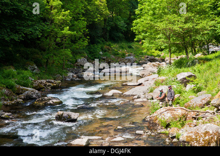 Due persone di mezza età pescatori pesca sportiva sulle rive del fiume Lyn nel Devon. Foto Stock