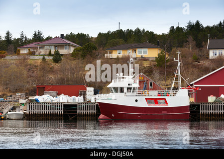 Piccolo rosso e bianco barca da pesca sta ormeggiata in Norvegia città costiera Foto Stock