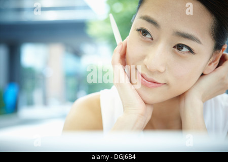 Una donna di pensare con una penna in mano Foto Stock