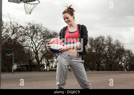 Donna che mantiene netball alla cintola Foto Stock