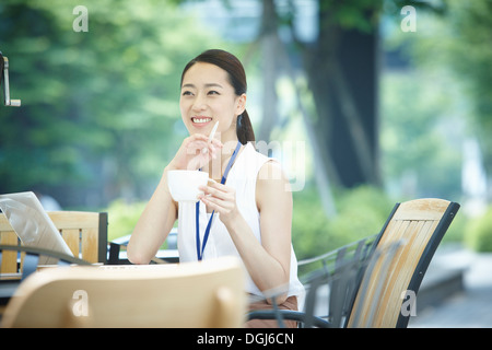 Una donna seduta a un coffee shop e sorridente Foto Stock