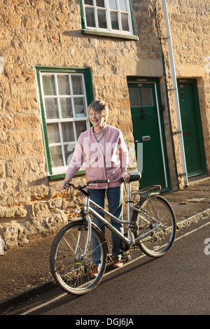 Senior uomo spingendo la sua bicicletta su strada Foto Stock