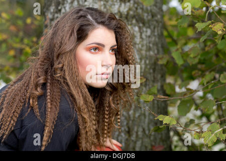 Giovane donna con capelli lunghi nella parte anteriore di un albero verticale Foto Stock