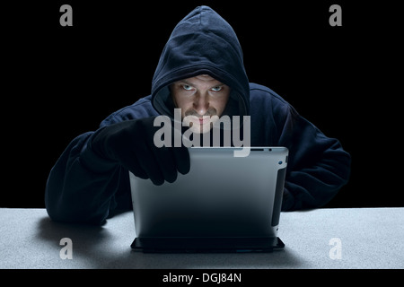 Un uomo incappucciato che rappresenta un cyber criminali. Foto Stock