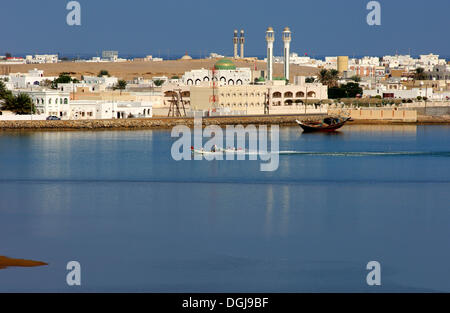 Barche a motore sulla laguna blu nella parte anteriore del case bianche della città portuale di Sur nel Golfo di Oman, il sultanato di Oman Foto Stock