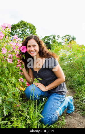 Ritratto di giovane donna azienda fiore rosa in allotment Foto Stock
