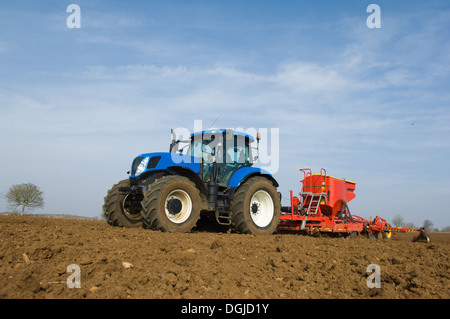 Trattore tirando attrezzature per semi di piante nel campo Foto Stock