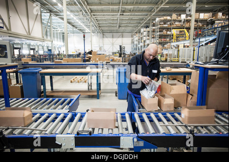 Maschio lavoratore magazzino imballaggio scatole di cartone per il nastro trasportatore Foto Stock