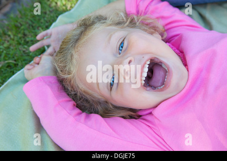 Ragazza distesa verso il basso con la bocca aperta, sorridente Foto Stock