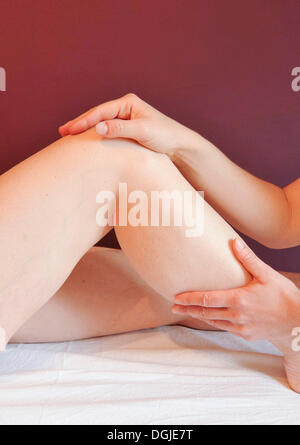 Le mani di un terapeuta di trattare il ginocchio di una giovane donna, massaggi medicinali Foto Stock