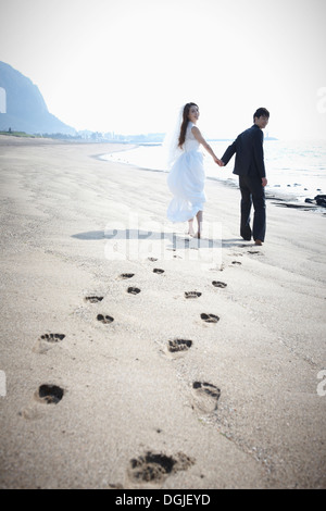 Gli sposi di camminare sulla spiaggia Foto Stock