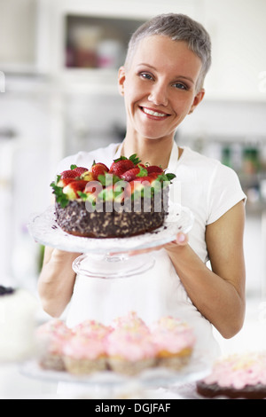 Ritratto di donna tenendo la torta con le fragole Foto Stock