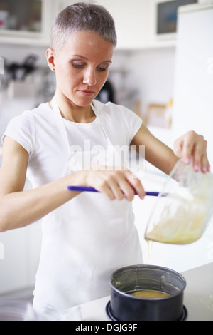 Donna versando la miscela la torta nella teglia per torte Foto Stock