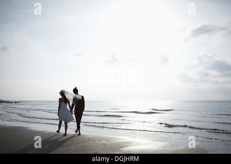 Gli sposi di camminare sulla spiaggia Foto Stock