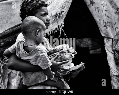 Casta inferiore Indian ragazza adolescente e figlio riceve cibo gratuito al di fuori del suo bender. Andhra Pradesh, India. Monocromatico Foto Stock