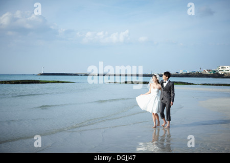 Gli sposi di camminare sulla spiaggia Foto Stock