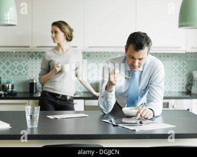 Imprenditore maturo utilizzando tablet a colazione in cucina Foto Stock