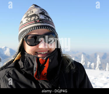 Giovane donna con la norvegese cappello e occhiali da sole in un paesaggio invernale Foto Stock