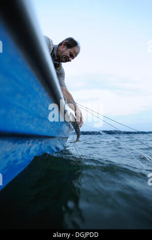 Il pescatore Johann Strobl casting per pescare sul Lago di Starnberg, area Fuenfseenland, Alta Baviera, Baviera Foto Stock