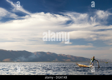 Gamba pescatore di canottaggio e gettando le sue reti sul Lago Inle in Myanmar. Foto Stock