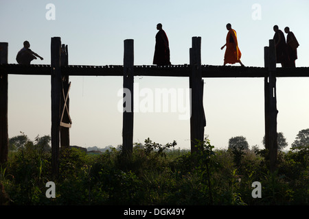 I monaci attraversando U Bein Teak ponte attraverso il lago Taungthaman in Myanmar. Foto Stock