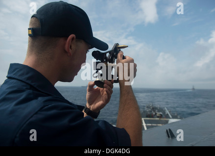 Alfiere Jed Teobaldo utilizza un sestante per misurare la distanza tra il Arleigh Burke-class guidato-missile cacciatorpediniere USS Preble Foto Stock