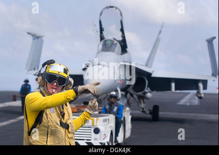 Aviazione di Boatswain Mate (manipolazione) 1a classe Jathan Lane dirige un'F/A-18C Hornet, assegnato all'Ragin' tori di Strike Fighter Squadron (VFA) 37 sul ponte di volo della portaerei USS Harry Truman (CVN 75). Harry Truman, ammiraglia per t Foto Stock