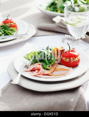 Piastre di prosciutto cotto smaltato con pomodori ripieni di spinaci e Foto Stock