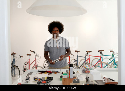 Uomo maturo a lavorare nel negozio di riparazione di biciclette Foto Stock