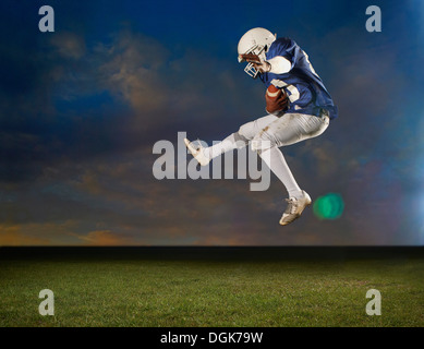 Giocatore di football americano jumping metà aria Foto Stock