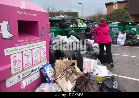 La donna lo scarto di immondizia in un traboccante di riciclaggio dei rifiuti al punto di alloggiamento Peachcroft Estate a Abingdon. Foto Stock