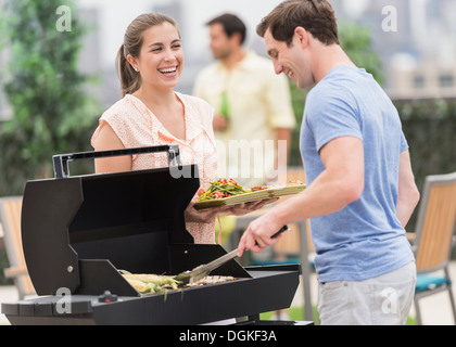 Gli amici sorseggiando un barbecue in giardino Foto Stock