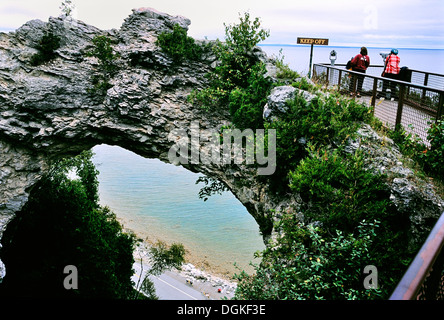 Arco di roccia a isola di Mackinac, Michigan, Stati Uniti d'America. I turisti alla ricerca attraverso i telescopi si affacciano. Strada costiera a fondo arch. Foto Stock