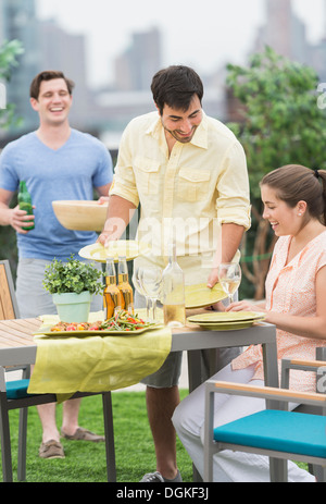 Gli amici sorseggiando un barbecue in giardino Foto Stock