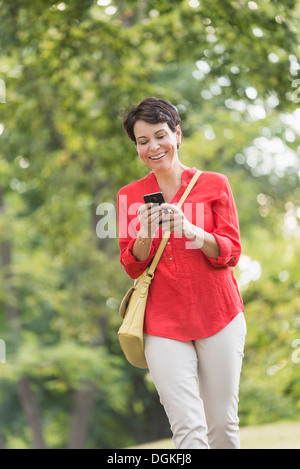 Donna matura per la messaggistica di testo in posizione di parcheggio Foto Stock