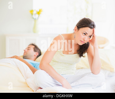 Triste donna in camera da letto, l'uomo dorme Foto Stock