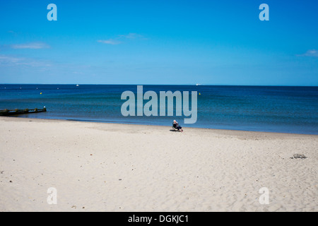 Una donna seduta sulla spiaggia a Swanage. Foto Stock