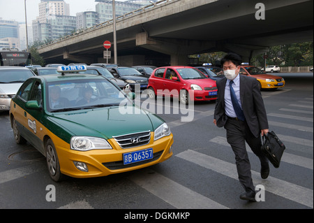 Un uomo che indossa una maschera rushing attraversare la linea di zebra a Pechino in Cina. 22-ott-2013 Foto Stock