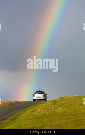 Un arcobaleno su strada vicino a Cox Tor nel Parco Nazionale di Dartmoor. Foto Stock