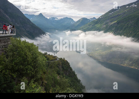 Il Geirangerfjord con navi da crociera, vista dal punto di vedetta su Eagle strada attraverso la nebbia verso le montagne nella parte posteriore, Geiranger Foto Stock