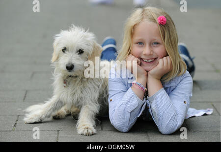 Ragazza con una razza mista cucciolo sdraiato su un marciapiede Foto Stock