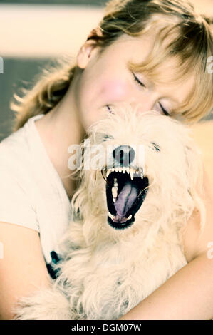 Ragazza, 9, cuddling con un giovane di mixed-cane di razza Foto Stock