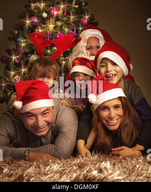 Closeup ritratto della grande famiglia felice con Babbo Natale sdraiati vicino ad albero di Natale, vacanze celebrazione, di gioia e di felicità Foto Stock