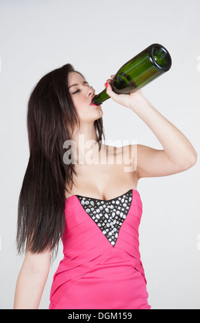 Parte femmina goer holding palloncini e bere da una bottiglia di vino Foto Stock