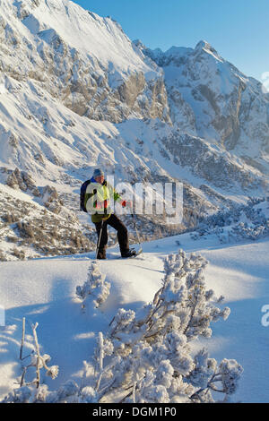 Uomo di fare escursioni con le racchette da neve, tour con racchette da neve su torrener joch pass, border Salisburgo - Berchtesgaden, guardando verso hohes brett mountain Foto Stock