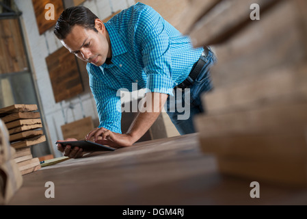 Un giovane uomo in una officina con una tavoletta digitale nel suo lavoro. Foto Stock